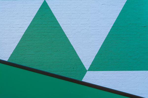 Green and blue painted brick wall in a bold geometric triangle pattern