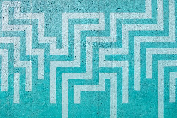 Turquoise wall with repeating geometric maze pattern